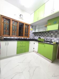 a green and white kitchen with green cabinets at Flickstays Elara in Bangalore +68 photos