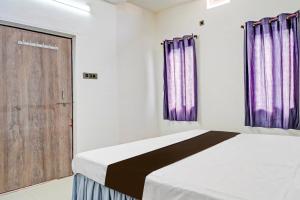 een slaapkamer met een bed met paarse gordijnen en een deur bij Hotel O Dream Star in Bhilai