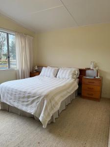a bedroom with a large bed and a window at Marlins Beach Shack Broulee in Broulee