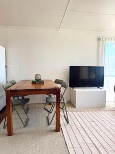 a living room with a wooden table and a flat screen tv at Marlins Beach Shack Broulee in Broulee +3 photos