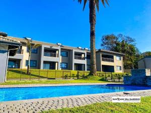 an apartment building with a swimming pool and a palm tree at Sun-Ash Sea Gardens in Port Shepstone
