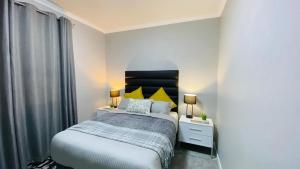 a bedroom with a bed with two night stands and two lamps at Sun-Ash Sea Gardens in Port Shepstone
