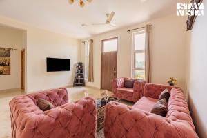 a living room with two couches and a tv at StayVista at Casa Shwika with Pool and Lawn in Hyderabad