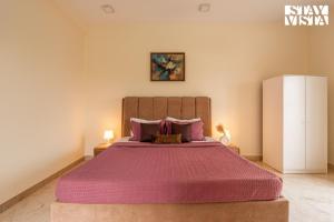a bedroom with a large bed with a pink bedspread at StayVista at Casa Shwika with Pool and Lawn in Hyderabad