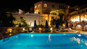 a swimming pool with chairs and umbrellas in front of a building at Grand Elite Cave Suites in Goreme +18 photos