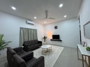 a living room with two couches and a tv at Harees Homestay in Kuala Lipis