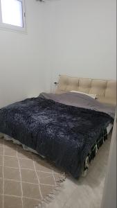 a bed in a white room with a black blanket at Sony in Kelibia