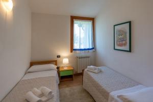 a small room with two beds and a window at Bungalow S3 in Isola Albarella +32 photos