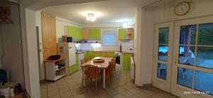 een keuken met groene kasten en een tafel en stoelen bij Magyar Tenger Pihenőház, 4-8 főre Balatonakarattya in Balatonakarattya