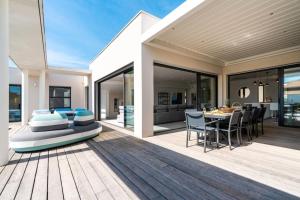 een patio van een huis met een tafel en stoelen bij Villa Boston luxury home with pool and Cali vibes in Le Grau-dʼAgde