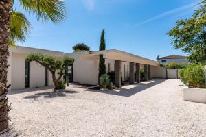 une vue extérieure d'une maison avec un palmier dans l'établissement Villa Boston luxury home with pool and Cali vibes, au Grau-dʼAgde