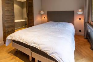 Un dormitorio con una gran cama blanca en una habitación. en La Forêt 15, en Méribel