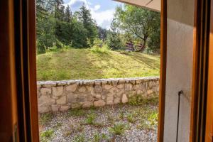 Una vista de un muro de piedra desde una ventana. en La Forêt 15, en Méribel