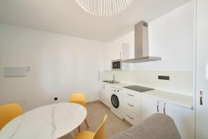 een witte keuken met een tafel en gele stoelen bij Eryan II in San José