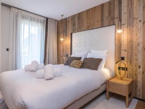 - une chambre avec un grand lit blanc et un mur en bois dans l'établissement Appartement moderne 3 chambres près des pistes avec parking Méribel - FR-1-565-108, à Les Allues