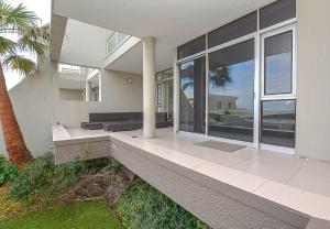 una casa bianca con una veranda con una palma di Spacious Beach Access Apartment at Dolphin Beach a Bloubergstrand