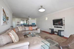 un soggiorno con un divano e una TV di Spacious Beach Access Apartment at Dolphin Beach a Bloubergstrand