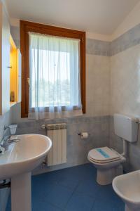 a bathroom with a sink and a toilet and a window at Bungalow S3 in Isola Albarella