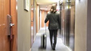 a woman walking down a hallway with a suitcase at Evenia Rocafort in Barcelona