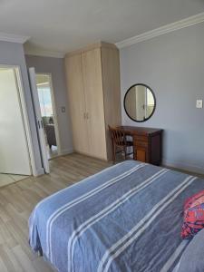 Un dormitorio con una cama, un escritorio y un espejo. en Coastal Bliss Steps from Beach, en Cape Town