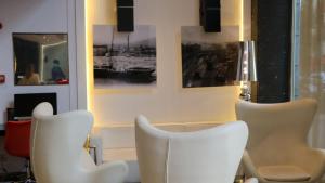 a living room with white chairs and paintings on the wall at Evenia Rocafort in Barcelona