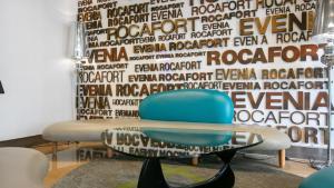 a room with a blue chair in front of a wall at Evenia Rocafort in Barcelona
