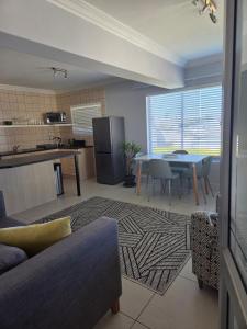Una cocina y una sala de estar con una mesa y un sofá. en Coastal Bliss Steps from Beach, en Cape Town