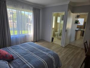 1 dormitorio con cama, ventana y baño en Coastal Bliss Steps from Beach, en Cape Town 5 fotos más