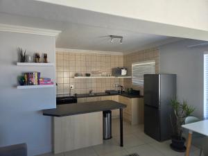 Una cocina con un refrigerador y una mesa dentro. en Coastal Bliss Steps from Beach, en Cape Town