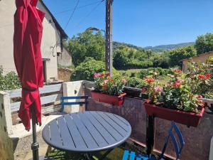 a blue table and chairs on a balcony with flowers at Maisonnette du Foirail in Espalion