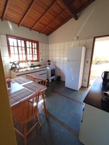 a kitchen with a table and a white refrigerator at Chalé da Lili in Nova Friburgo