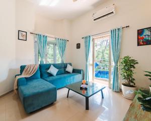 a living room with a blue couch and a table at Villa Sylvana By Bluewave Hospitality in Nagoa-Bardez