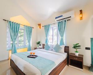 a bedroom with a large bed with blue curtains at Villa Sylvana By Bluewave Hospitality in Nagoa-Bardez +19 photos