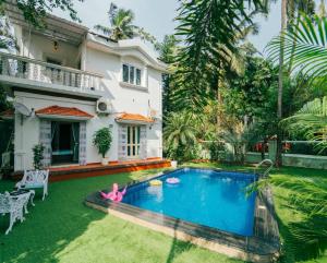a villa with a swimming pool in front of a house at Villa Sylvana By Bluewave Hospitality in Nagoa-Bardez