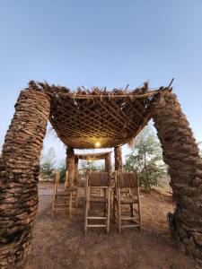 a group of chairs sitting under a stone shelter at Camping Meteorite in Merzane