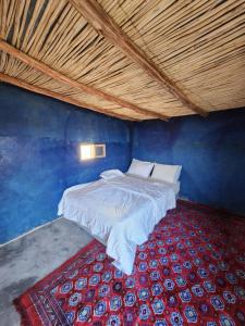 a bed in a blue room with a red carpet at Camping Meteorite in Merzane