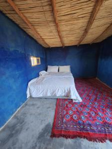 a bed in a blue room with a red rug at Camping Meteorite in Merzane