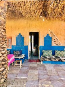 a house with blue walls and a thatched roof at Camping Meteorite in Merzane