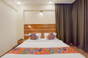 Un dormitorio con una cama grande con cabecero de madera. en FabHotel East Land, en Bangalore