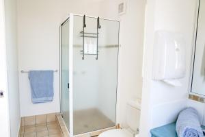 a glass shower in a bathroom with a blue towel at Seeside Cottage - See St Bargara in Bargara