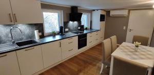 eine große Küche mit weißen Schränken und einem Tisch in der Unterkunft Chalet am Diemelsee - Ferienwohnung mit Terrasse im Sauerland in Heringhausen