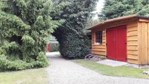 a smallshed with a red door in a garden at Ferienwohnung Sonneneck mit Boot und Kanu in Seedorf