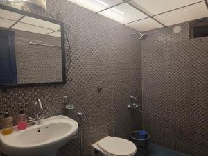 a bathroom with a sink and a toilet and a mirror at Baga Waves by Dia Hotels And Homes in Calangute