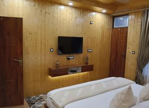 a bedroom with a tv on a wooden wall at Chatnya Homes Kasauli by Splendid Hotels - Family Groups Events in Kasauli