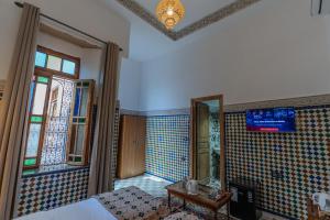 a bedroom with a bed and a tv on the wall at Riad Al Mozyane in Fez