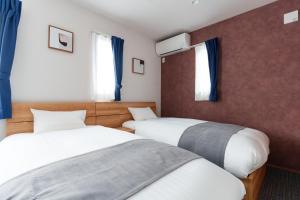 two beds in a room with blue curtains and windows at Villas Fuji Terrace ヴィラス富士テラス in Fujikawaguchiko