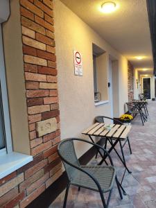 a group of tables and chairs next to a brick wall at Némó Apartman in Eger
