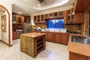 eine große Küche mit Holzschränken und einer Steinwand in der Unterkunft D Pool Villa Pattaya in Nong Prue