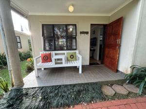 eine weiße Bank vor einem Haus in der Unterkunft Khaled Estate Cottages in Hillcrest + 22 Fotos