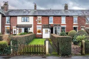 a red brick house with a fence in front of it at Ribby Stays - 2 bed Cottage Pet Friendly in Wrea Green